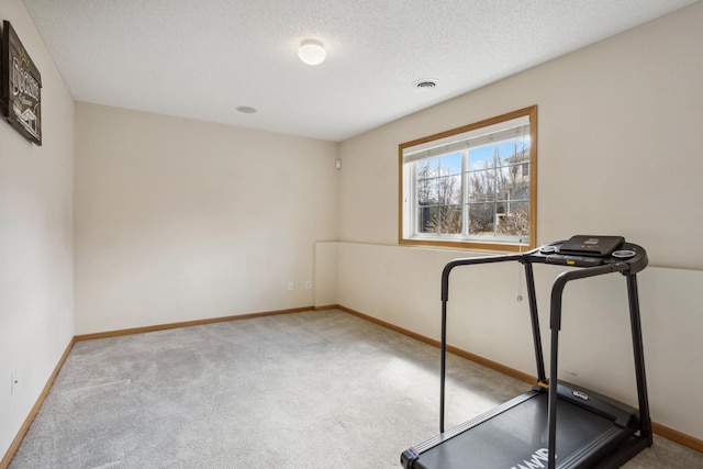 exercise area with baseboards, carpet, a textured ceiling, and visible vents