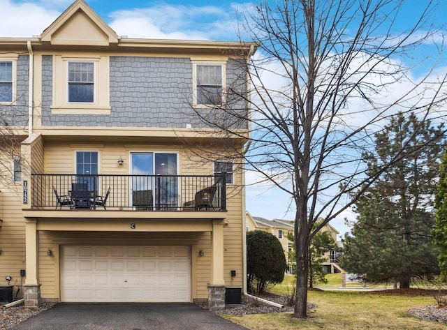 multi unit property featuring an attached garage, aphalt driveway, central air condition unit, and a balcony