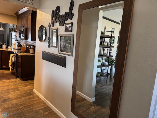 corridor with baseboards and dark wood finished floors