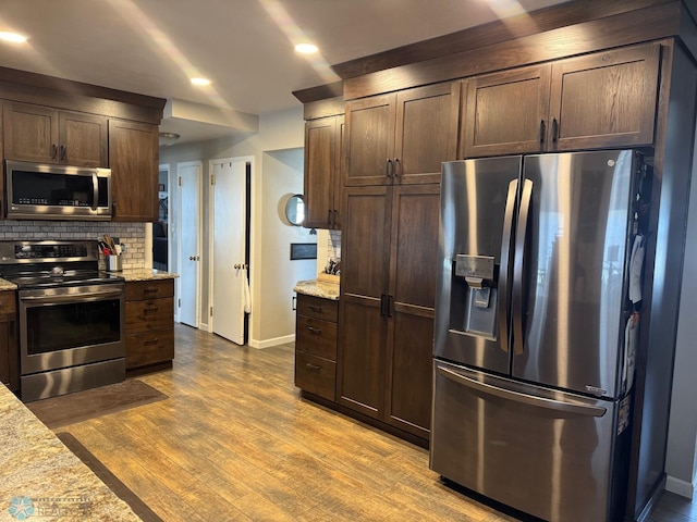 kitchen with stainless steel appliances, dark brown cabinetry, and baseboards