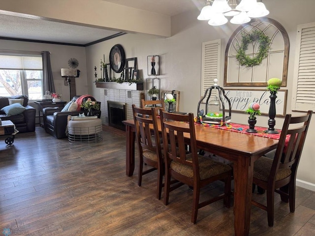 dining area with a brick fireplace, an inviting chandelier, and dark wood finished floors
