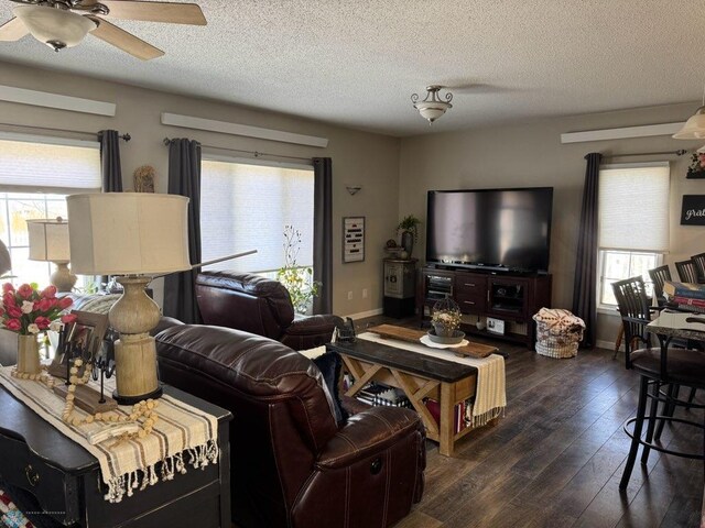 living area featuring a textured ceiling, ceiling fan, baseboards, and dark wood finished floors