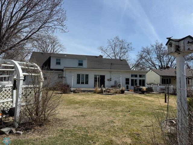 back of property featuring fence and a lawn