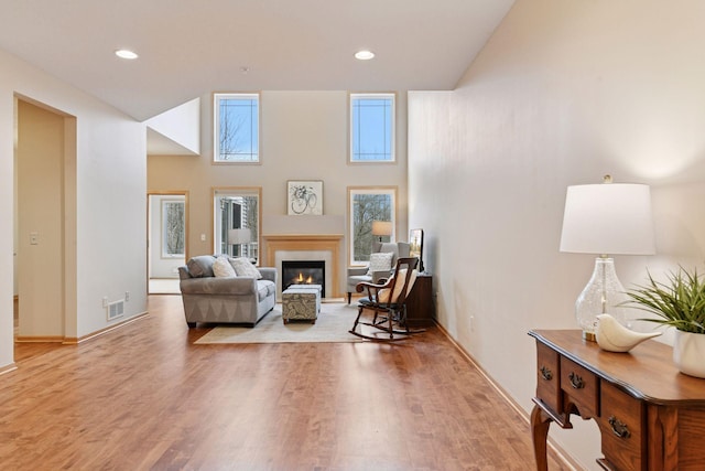 living room with a glass covered fireplace, recessed lighting, visible vents, and light wood-style flooring