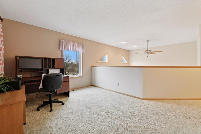 carpeted office space with ceiling fan and baseboards