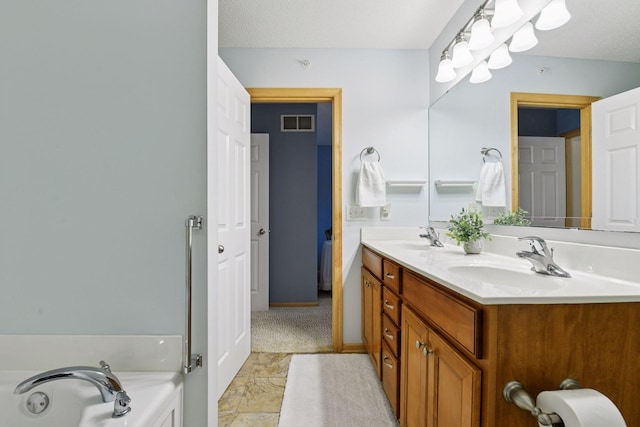 bathroom with a sink, visible vents, a bathing tub, and double vanity
