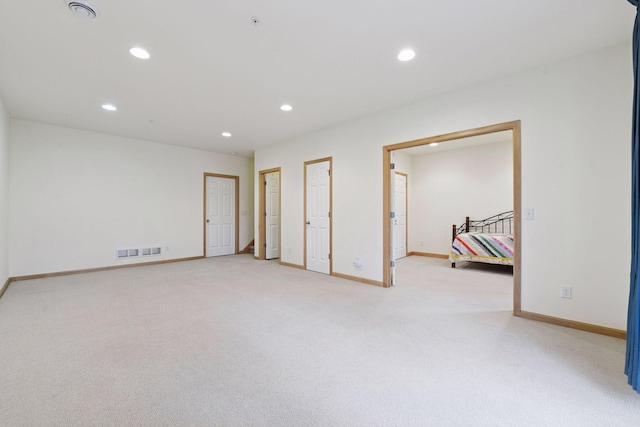 unfurnished room with recessed lighting, visible vents, light colored carpet, and baseboards