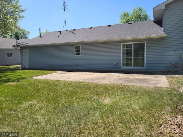 back of property with a patio, a lawn, and a shingled roof