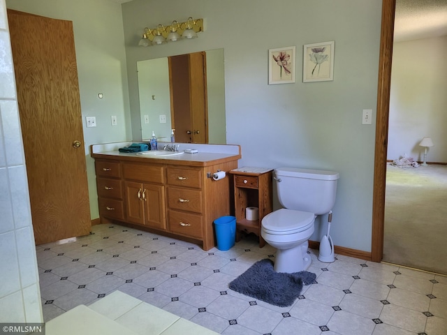 bathroom featuring toilet, vanity, and baseboards