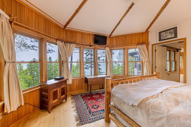 bedroom featuring wood walls, light wood-style floors, and lofted ceiling