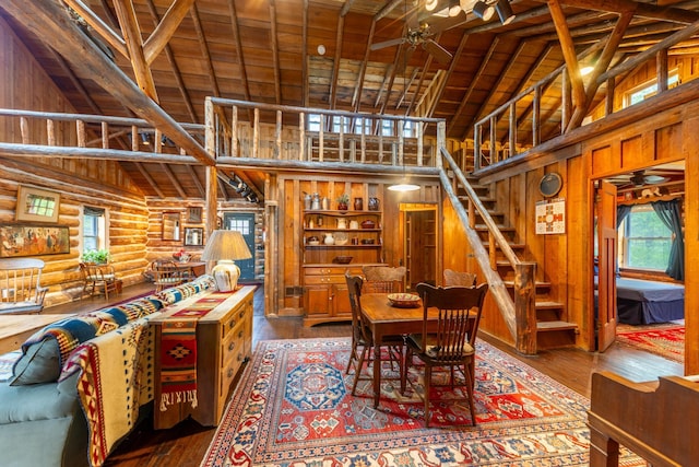 dining area with wood-type flooring, high vaulted ceiling, a ceiling fan, and stairs