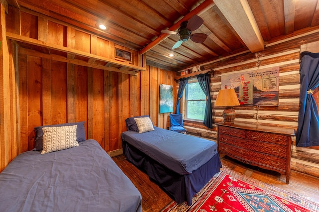 bedroom with wooden walls, visible vents, beam ceiling, hardwood / wood-style flooring, and wooden ceiling