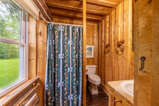 bathroom with vanity, toilet, wood finished floors, wood walls, and a shower with shower curtain