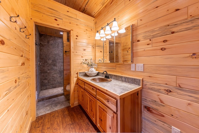 bathroom featuring wood walls, vanity, a shower stall, and wood finished floors