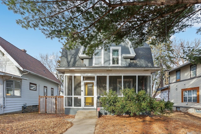 view of front of house featuring roof with shingles and a sunroom