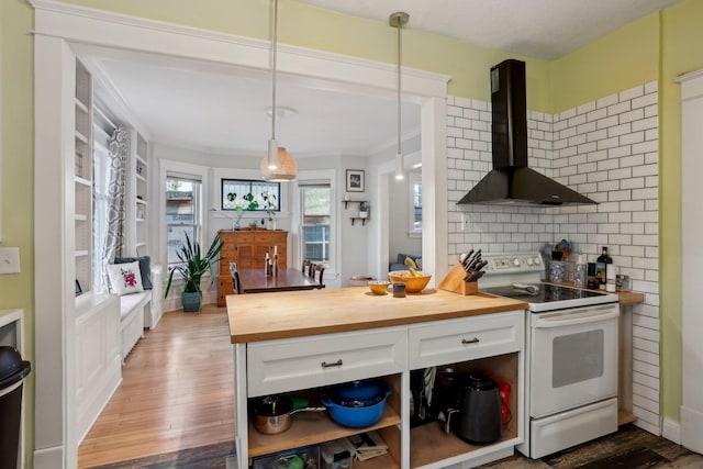 kitchen with wall chimney exhaust hood, electric range, white cabinetry, wood finished floors, and butcher block countertops
