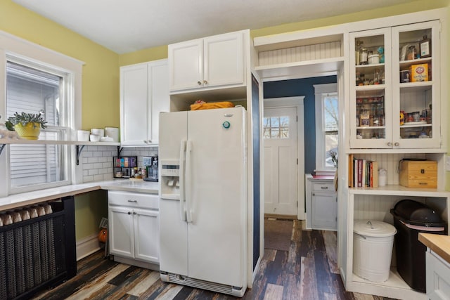 kitchen featuring light countertops, white fridge with ice dispenser, and plenty of natural light