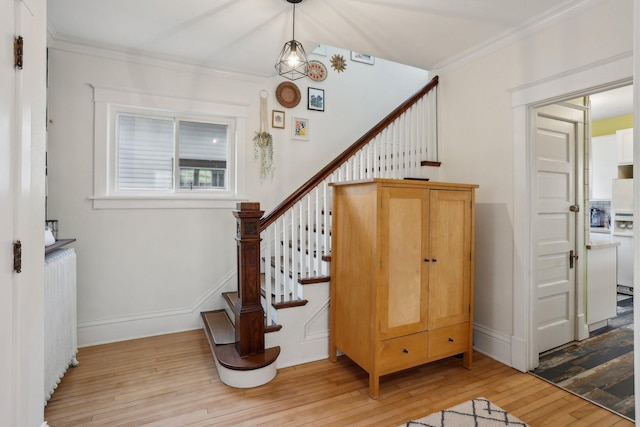 staircase with crown molding, radiator heating unit, baseboards, and hardwood / wood-style flooring
