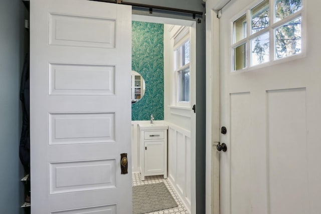 entryway featuring a decorative wall, wallpapered walls, and a wainscoted wall