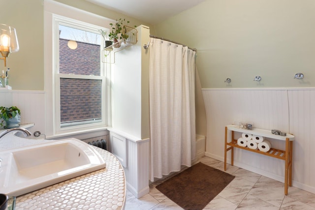 full bath featuring curtained shower, a sink, a tub, wainscoting, and marble finish floor