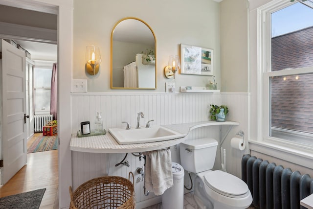 bathroom featuring radiator heating unit, a sink, and a wainscoted wall