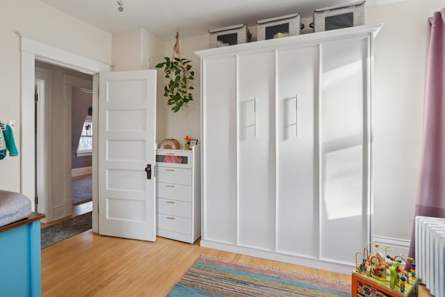 bedroom with radiator and light wood-style floors