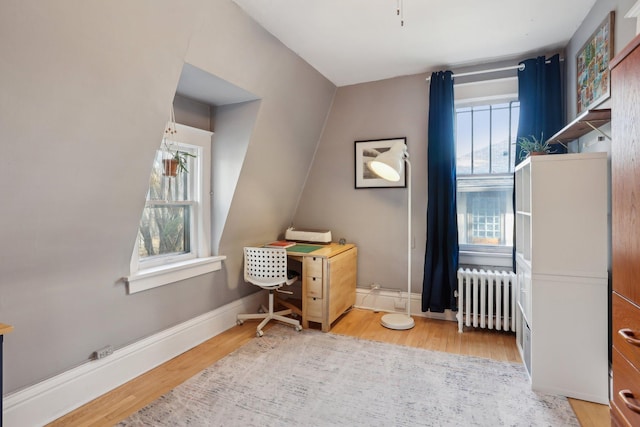 bedroom featuring baseboards, radiator, and wood finished floors