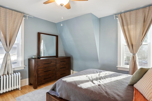 bedroom with radiator heating unit, hardwood / wood-style flooring, and ceiling fan