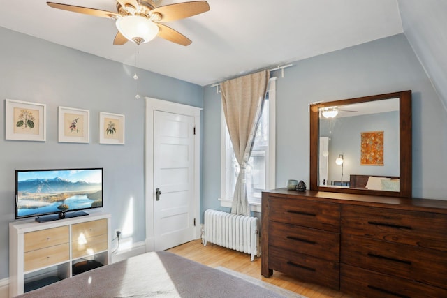 bedroom with radiator heating unit, a ceiling fan, and wood finished floors