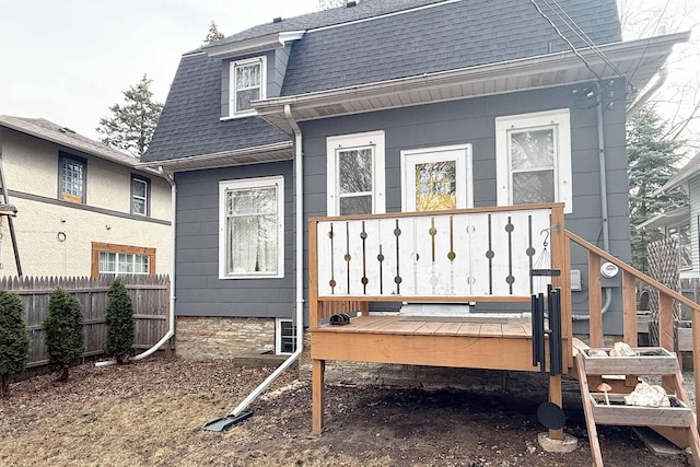 rear view of property featuring fence and a shingled roof