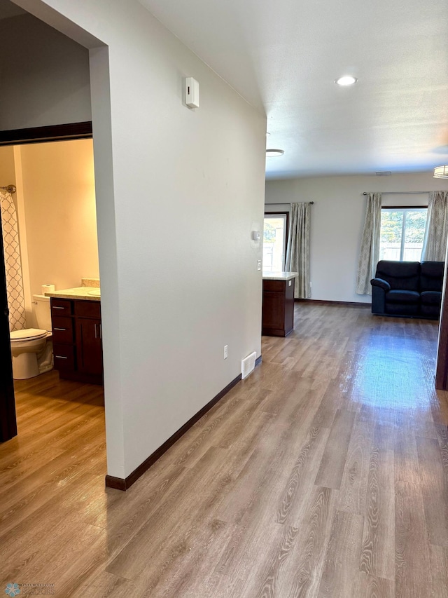 unfurnished living room featuring light wood-style flooring, baseboards, and visible vents