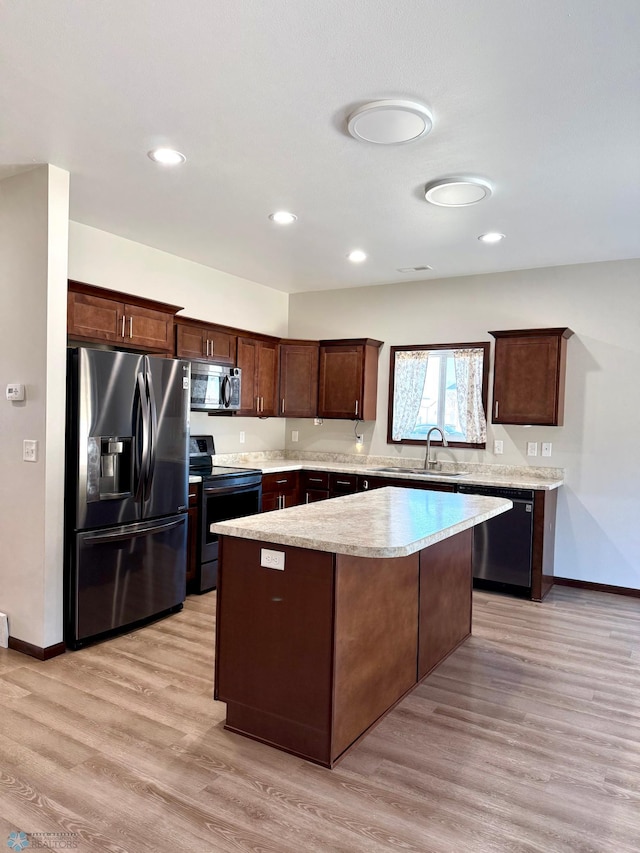 kitchen with light countertops, a kitchen island, light wood-style floors, appliances with stainless steel finishes, and a sink