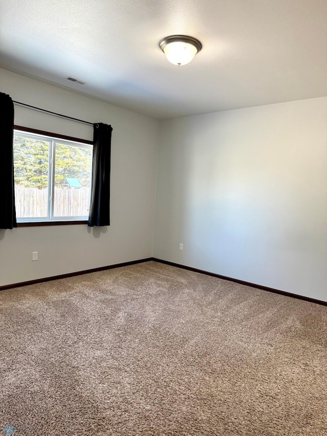 carpeted spare room with visible vents, baseboards, and a textured ceiling