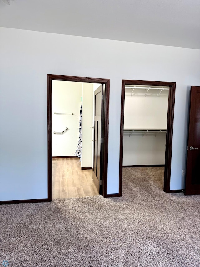 unfurnished bedroom featuring carpet floors, a spacious closet, a closet, and baseboards