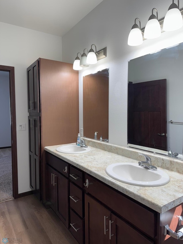 full bathroom with double vanity, a sink, and wood finished floors