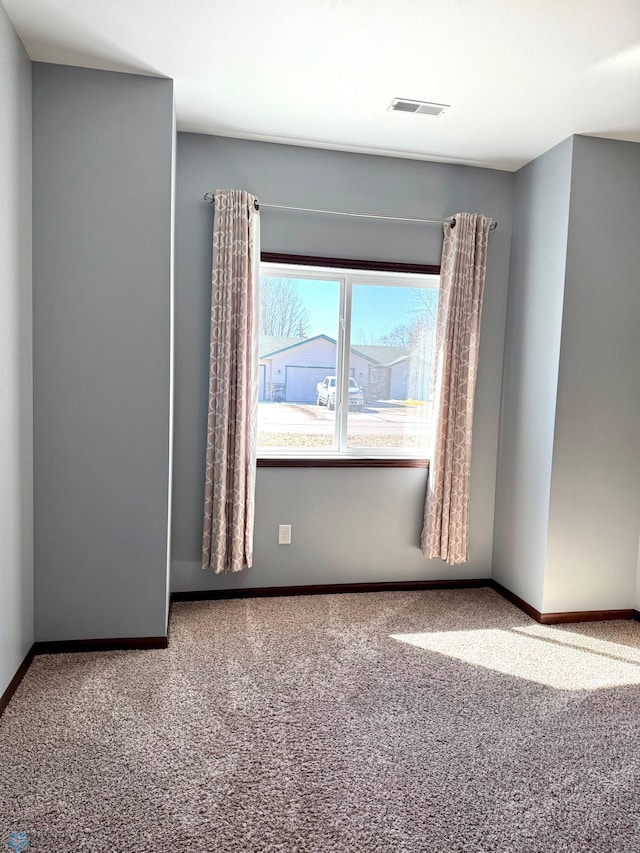 carpeted spare room with baseboards and visible vents