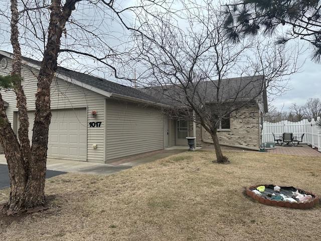1017 Clausen Ave SW, Bemidji, MN 56601 - view of side of property with driveway, fence, brick siding, an attached garage, and a yard