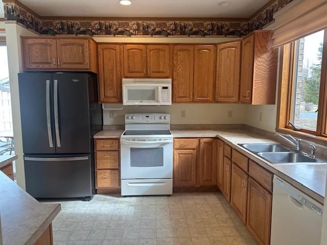 1017 Clausen Ave SW, Bemidji, MN 56601 - kitchen featuring brown cabinets, a sink, white appliances, and light countertops