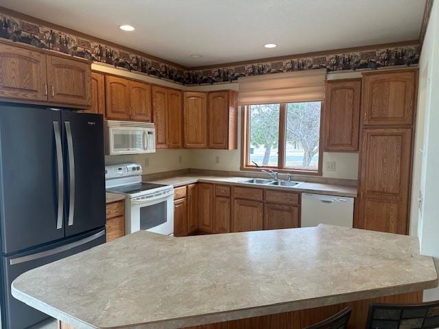 1017 Clausen Ave SW, Bemidji, MN 56601 - kitchen featuring a sink, brown cabinets, white appliances, a breakfast bar area, and light countertops