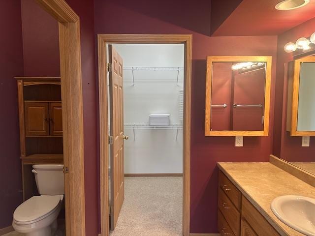 1017 Clausen Ave SW, Bemidji, MN 56601 - bathroom featuring baseboards, vanity, a walk in closet, and toilet