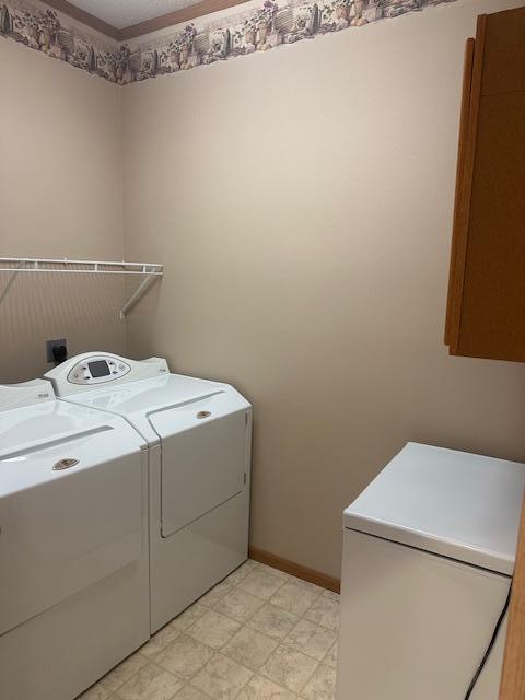 1017 Clausen Ave SW, Bemidji, MN 56601 - laundry area with light floors, baseboards, washer and clothes dryer, and cabinet space