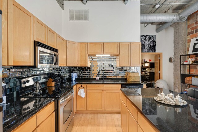 521 7th St Unit 311, Minneapolis, MN 55415 - kitchen with light brown cabinetry, appliances with stainless steel finishes, a towering ceiling, and visible vents