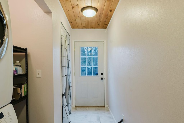 doorway featuring stacked washing maching and dryer, wood ceiling, baseboards, and marble finish floor