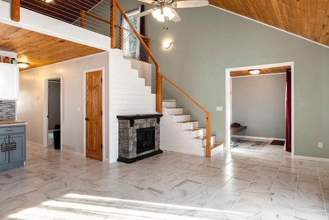 unfurnished living room with wooden ceiling, a ceiling fan, high vaulted ceiling, and stairs
