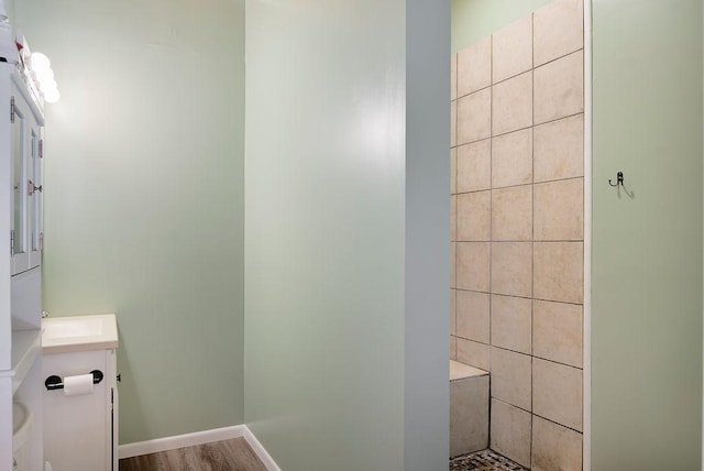 bathroom with tiled shower and wood finished floors
