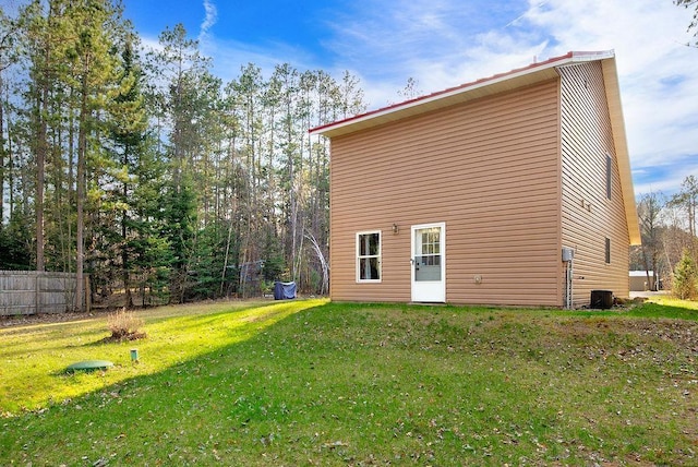back of property with central AC, fence, and a yard