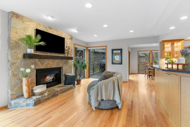 living area with light wood-style floors, baseboards, a fireplace, and recessed lighting