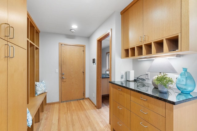 kitchen with dark stone counters, open shelves, baseboards, and light wood finished floors