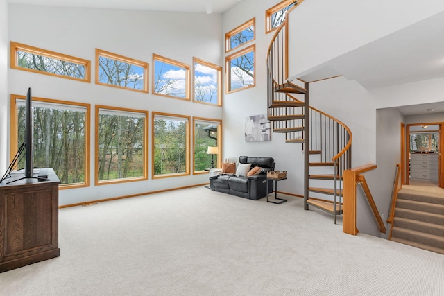living area featuring carpet floors, stairs, a high ceiling, and a healthy amount of sunlight