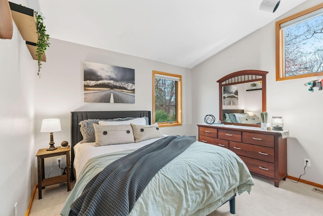 bedroom featuring baseboards, vaulted ceiling, light carpet, and multiple windows